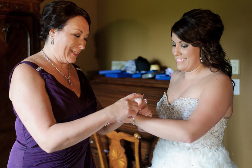 Mother putting bracelet on bride