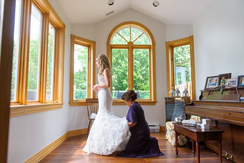 Mother helping bride with dress