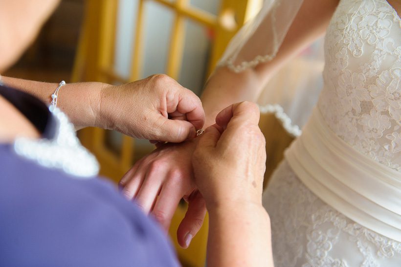 Mother helping with bride's bracelet