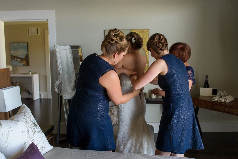 Bridesmaids putting on bride's dress