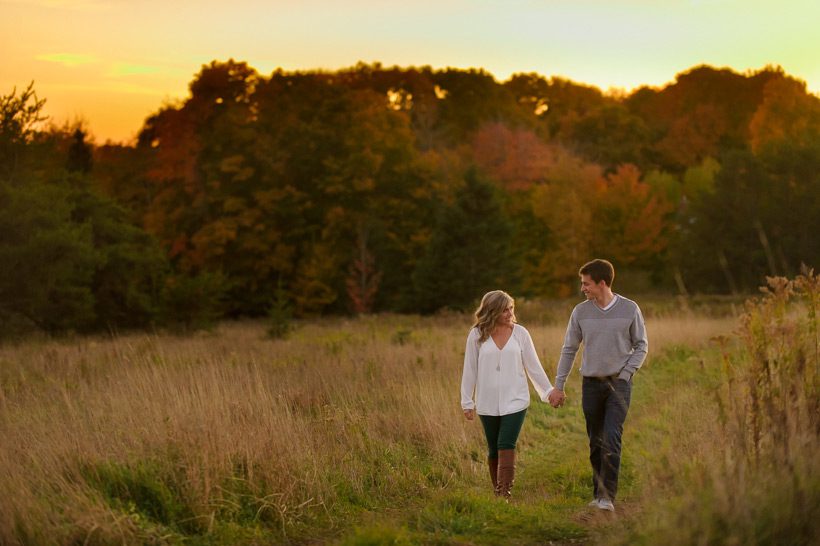 Couple walking in field at sunset