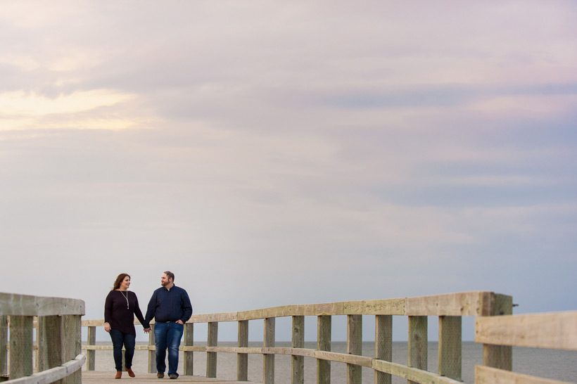 Couple walking on boardwalk with sunset