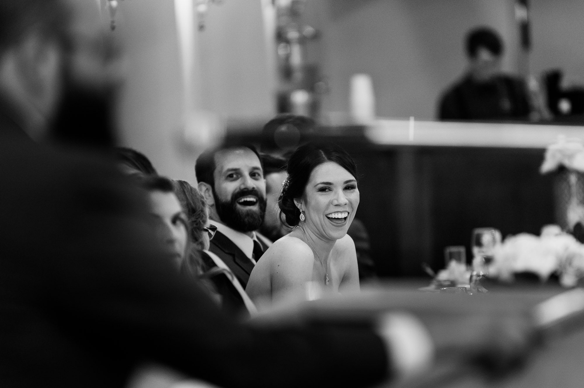 Bride and groom laughing during speeches