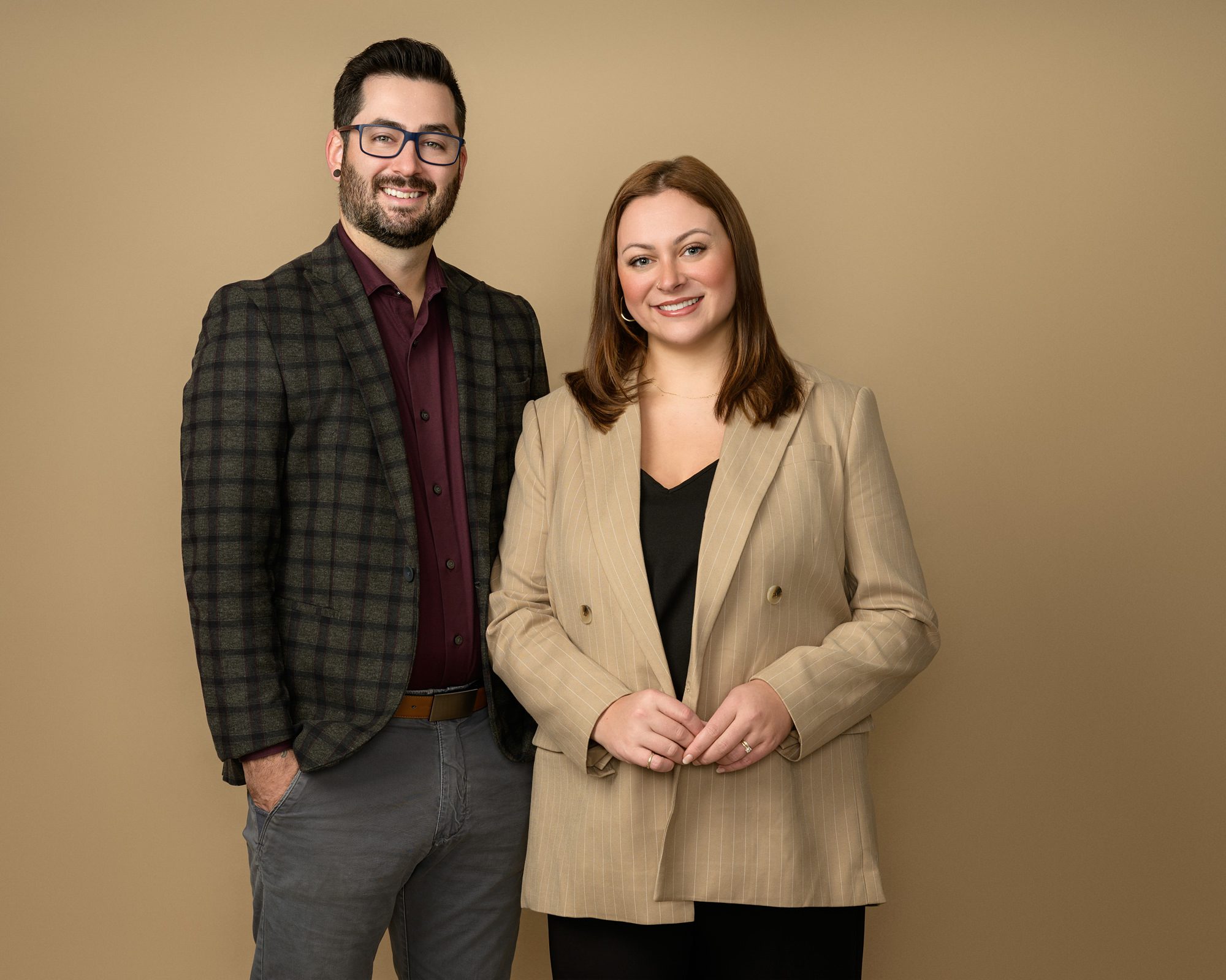 Business portrait of a real estate couple on a beige background.