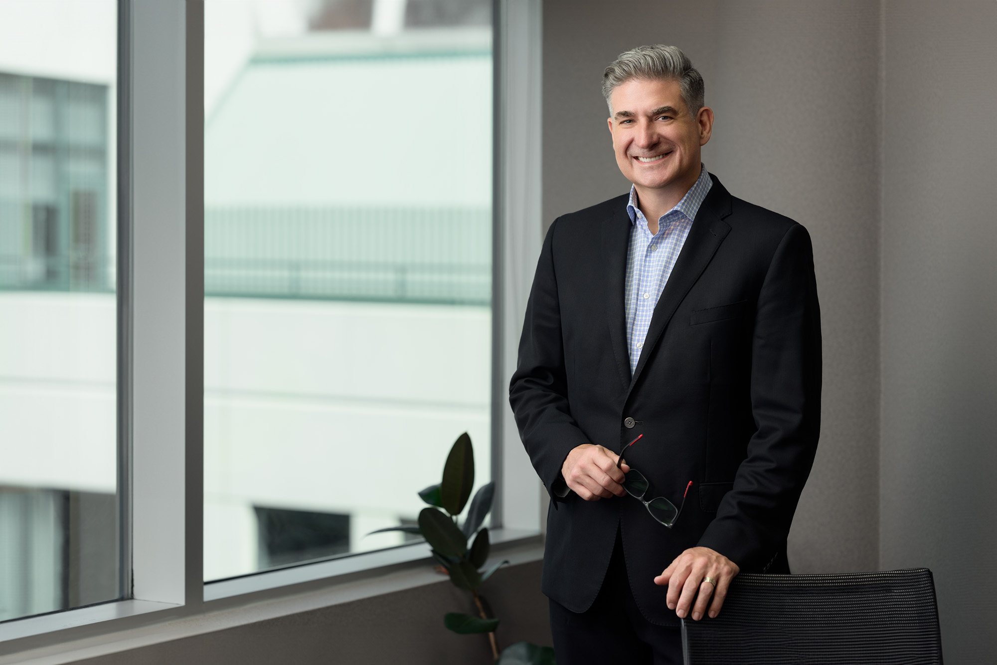 Portrait of a male financial planner in a corporate office with a view of the skyline through the windows.